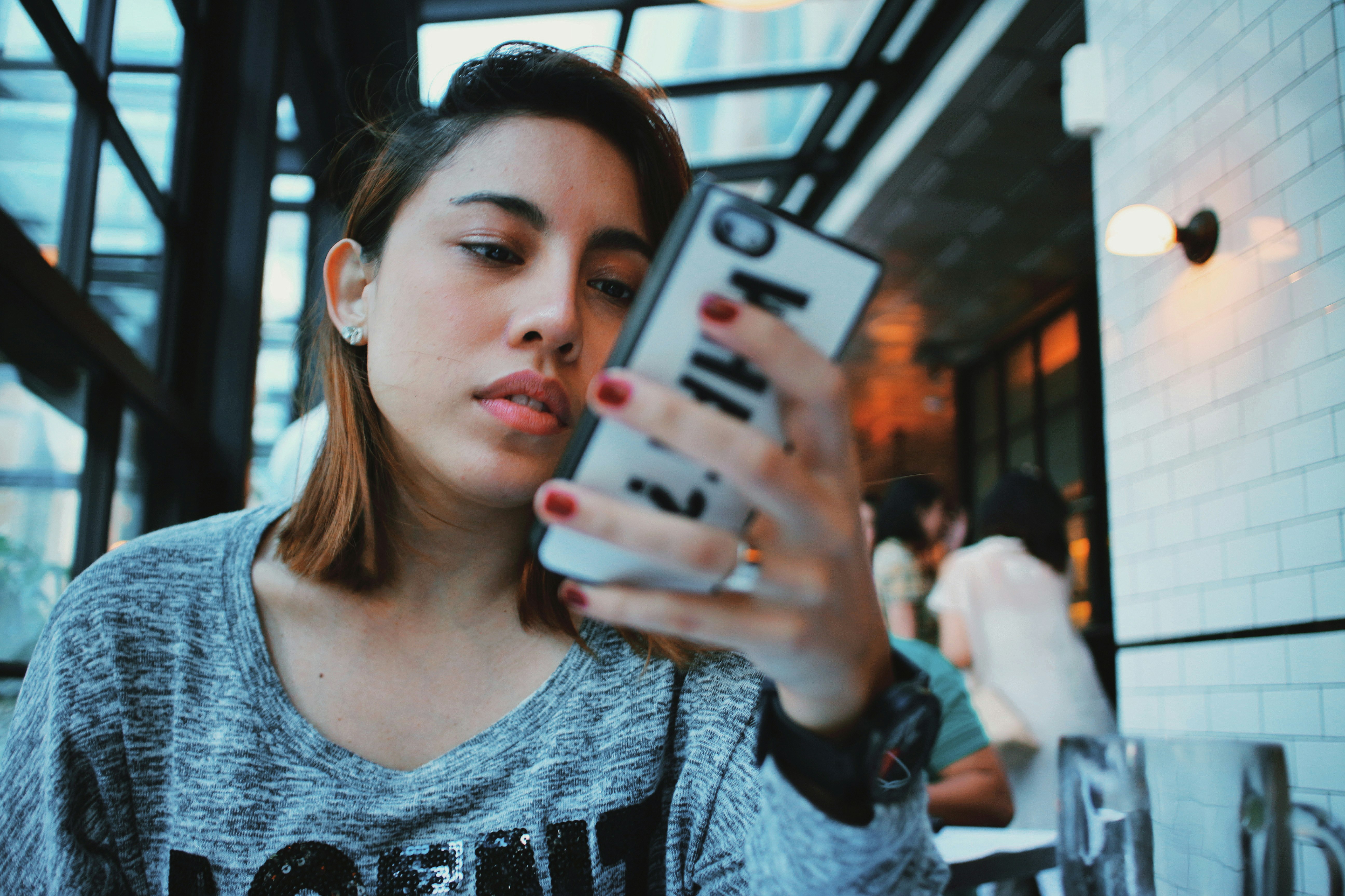 woman in gray and black sweater holding white and black iphone case